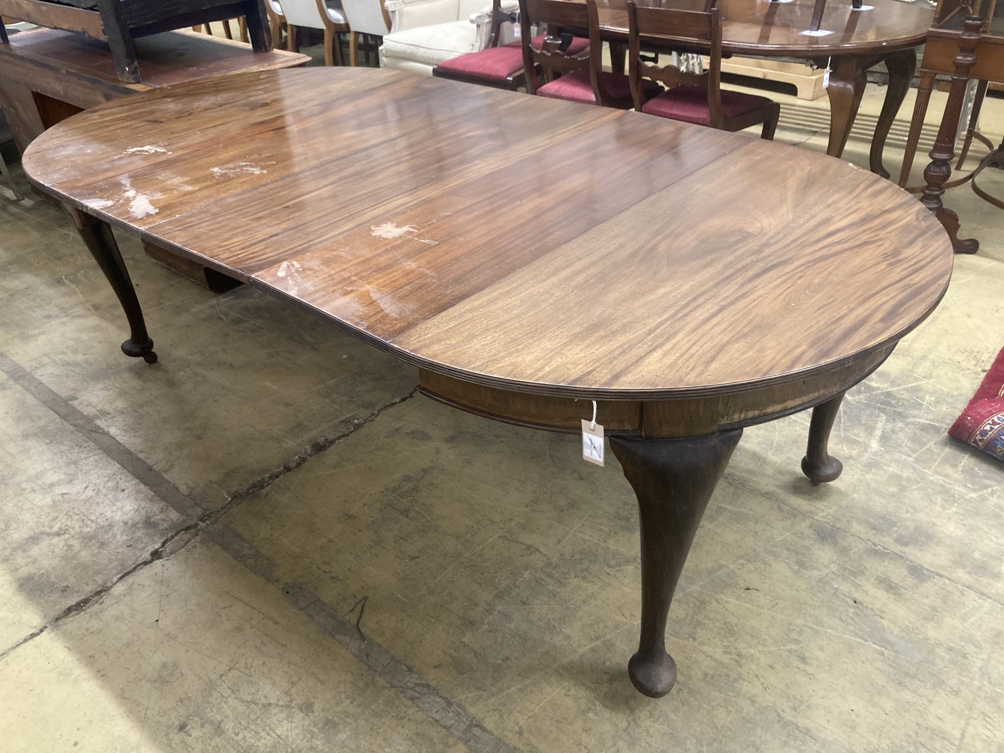 A 1920s circular mahogany extending dining table with three leaves and handle, length approx. 230cm extended, width 120cm, height 75cm